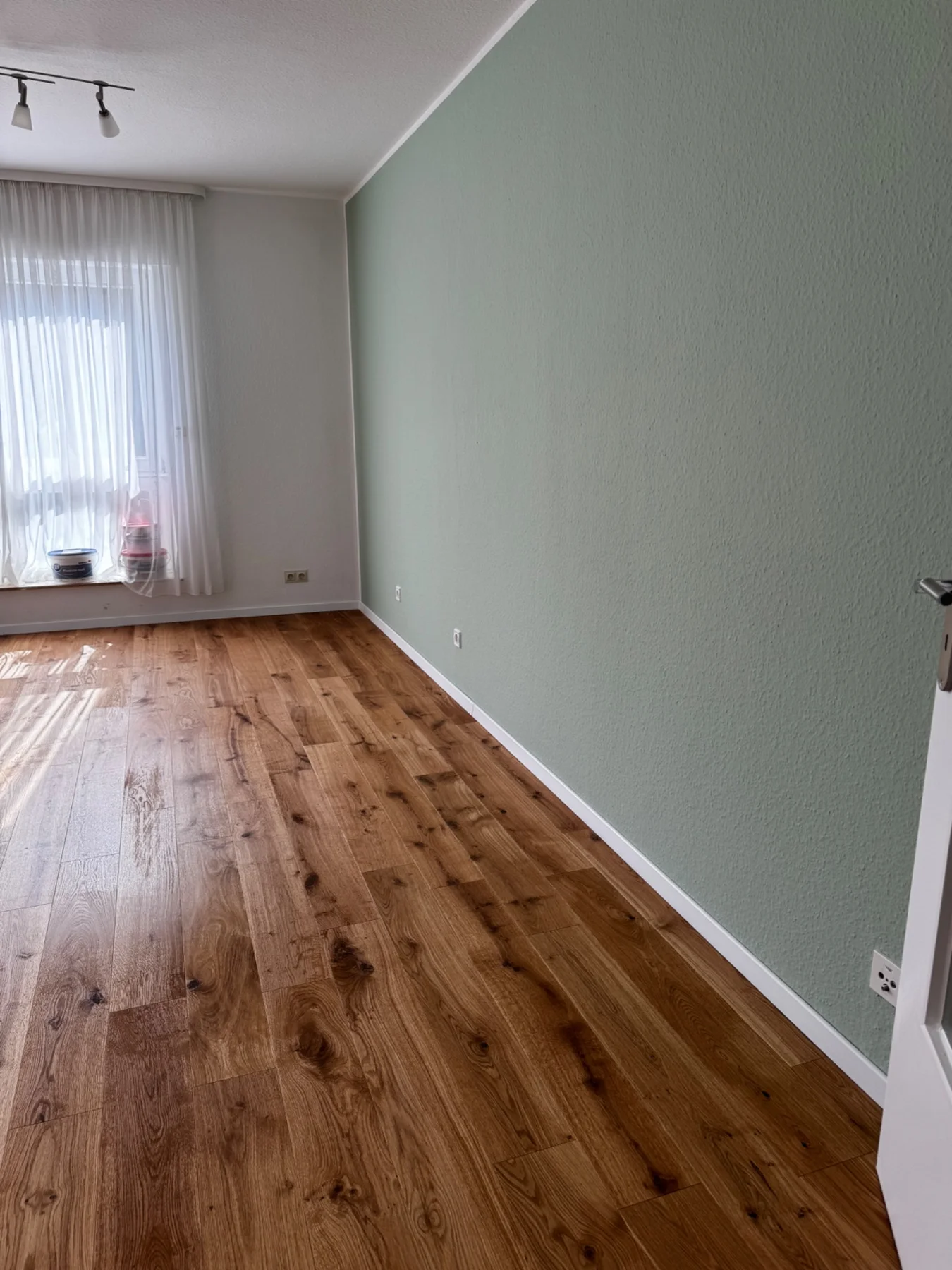 Fertig gestalteter Wohnraum mit dezent grünen Wänden und warmen Holztönen